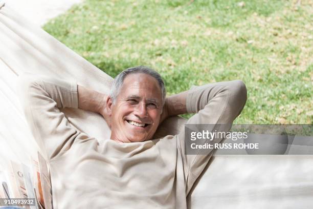man in hammock, hands behind head looking at camera smiling - hände hinter dem kopf stock-fotos und bilder
