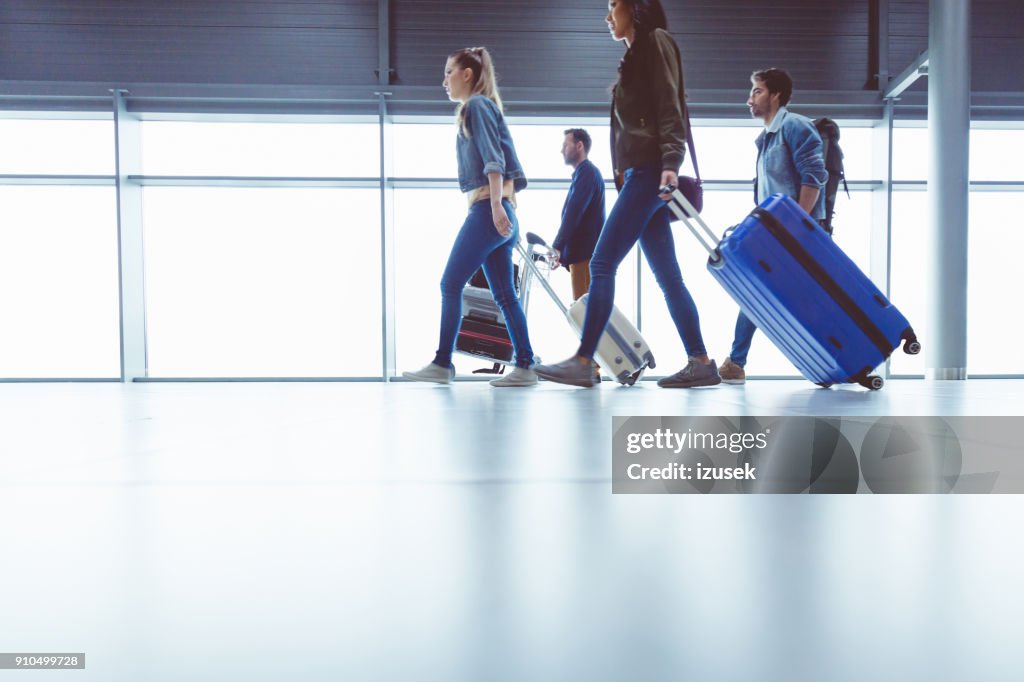 Side view of people walking with suitcase at airport terminal