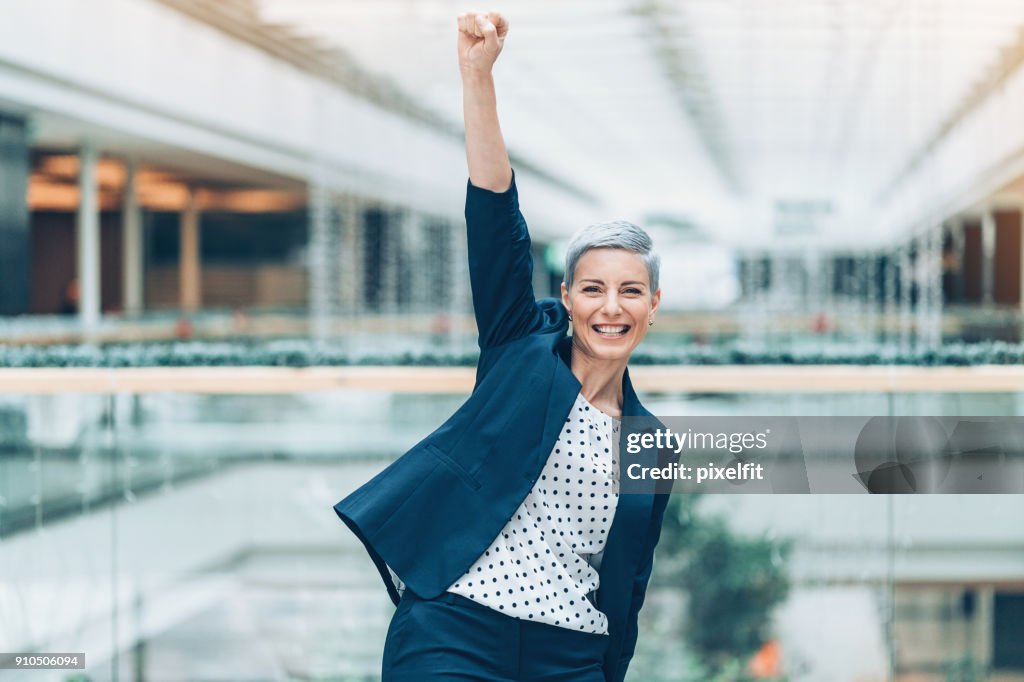 Happy businesswoman with arm raised in triumph