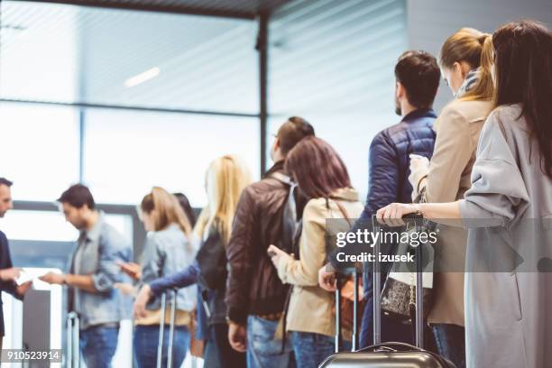 grupo de personas de pie en cola en la puerta de embarque - embarcar fotografías e imágenes de stock