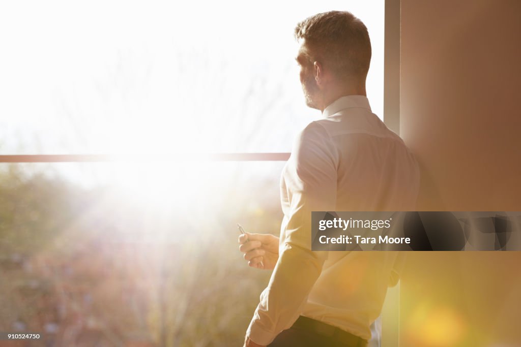 Business man standing my window with sunlight