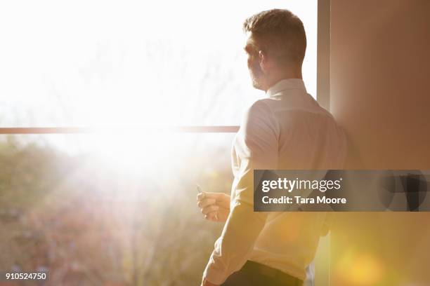 business man standing my window with sunlight - オフィス　レンズフレア ストックフォトと画像