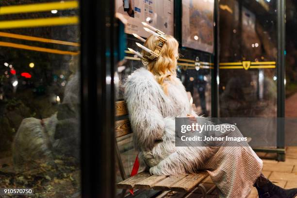 woman in fur coat sitting at bus stop at night - johner christmas bildbanksfoton och bilder