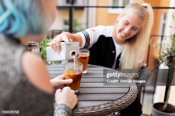 woman pouring milk into coffee - cartón de bebida fotografías e imágenes de stock