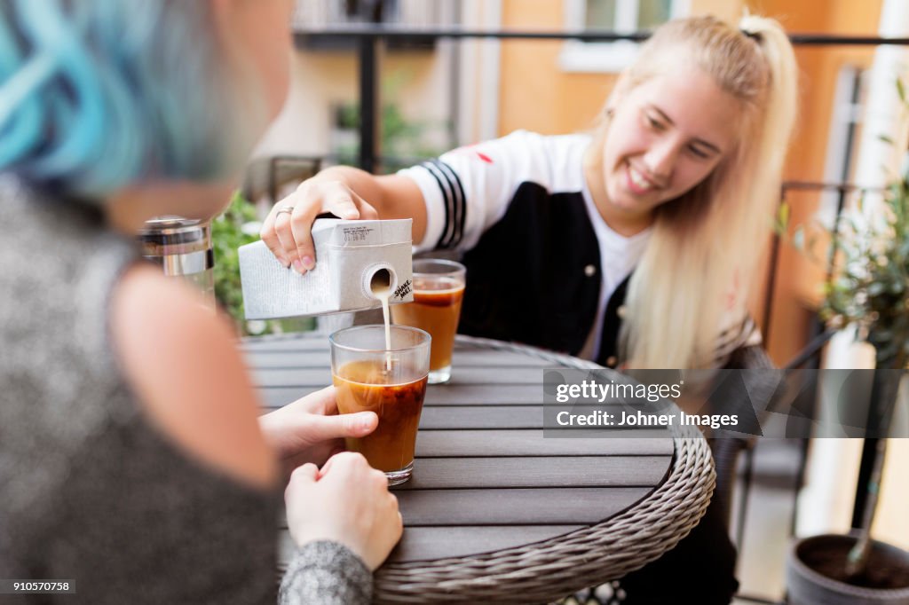 Woman pouring milk into coffee