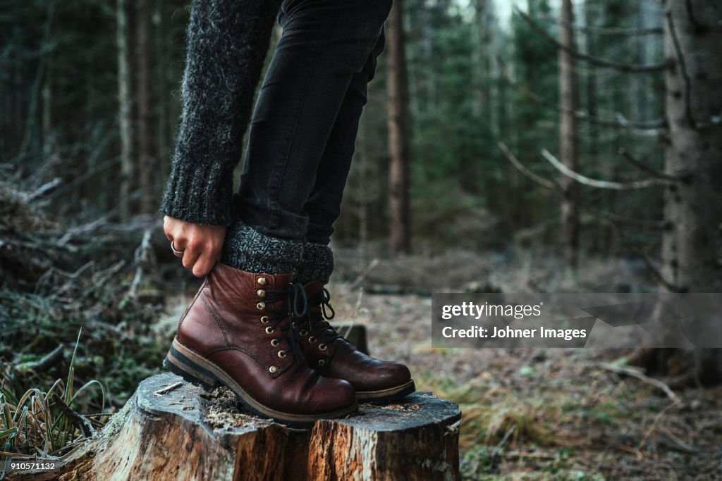 Woman in boots standing on a stump