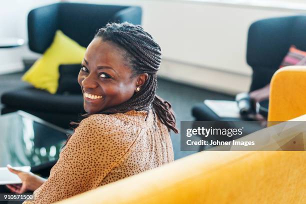 smiling woman sitting on sofa - dark skin stock pictures, royalty-free photos & images