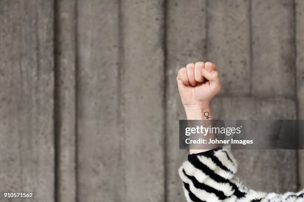 clenched fist and female symbol on arm - woman arm fist stock pictures, royalty-free photos & images
