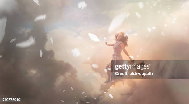 angel in sky with falling feathers - angels stock pictures, royalty-free photos & images