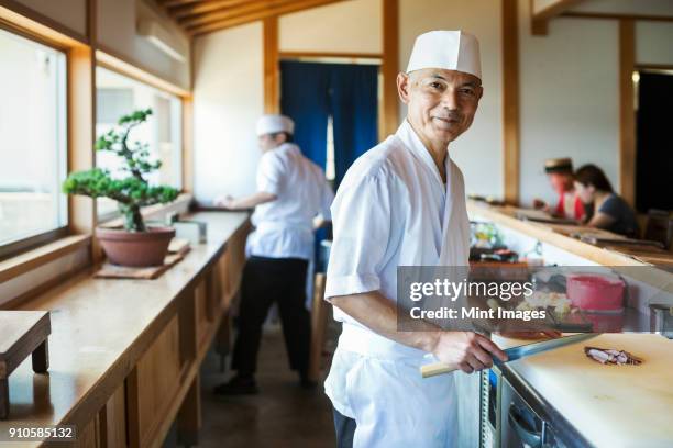 two chefs working at a counter at a japanese sushi restaurant. - sushi stock pictures, royalty-free photos & images