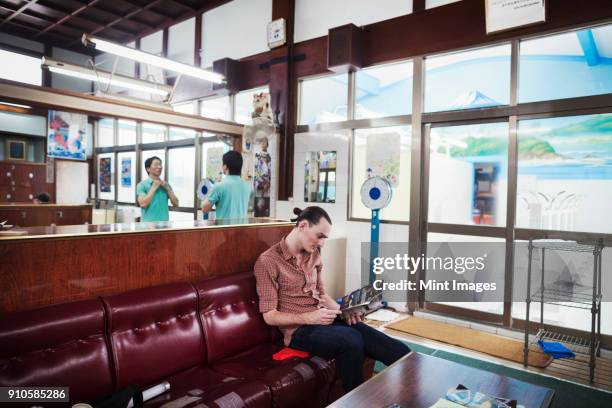 a public bath house, a young western man and a japanese man at reception. - bathhouse stock pictures, royalty-free photos & images