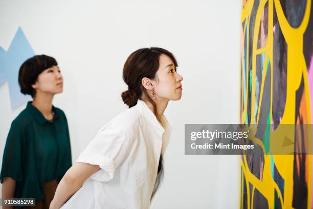 two women standing in an art gallery, looking at an abstract modern painting. - art of grenfell tower victim khadija saye on show in venice stockfoto's en -beelden