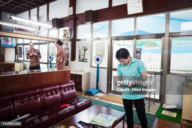 a public bath house, a young western man and a japanese man at reception. - badhuis stockfoto's en -beelden