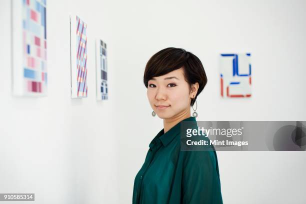 woman with short black hair wearing green shirt standing in art gallery, looking at camera. - black shirt 個照片及圖片檔