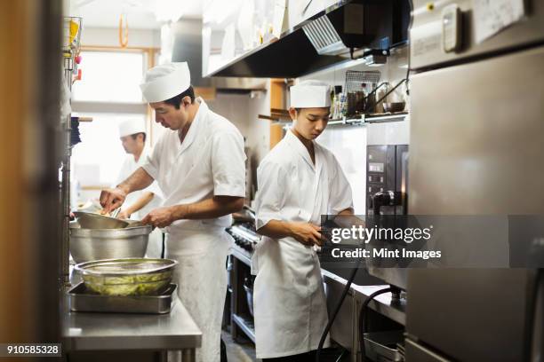 two chefs working in the kitchen of a japanese sushi restaurant. - kochlehrling stock-fotos und bilder