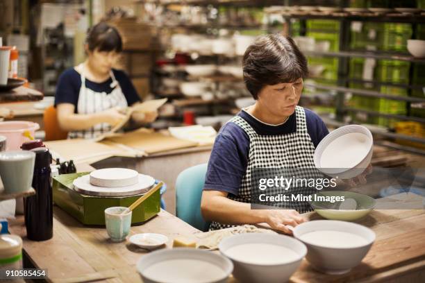 two women sitting in a workshop, working on japanese porcelain bowls. - traditional business stock pictures, royalty-free photos & images