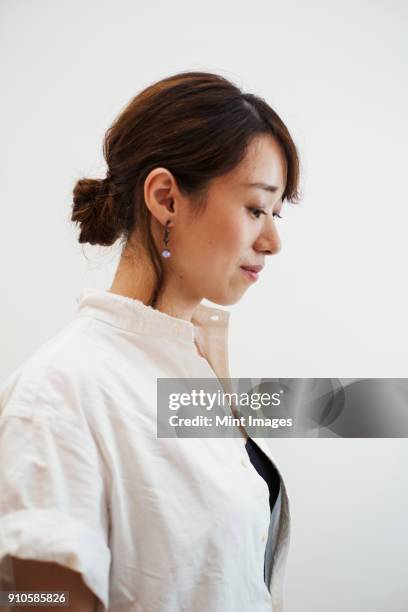 profile view of woman with ponytail wearing white shirt standing in art gallery. - hair back ストックフォトと画像