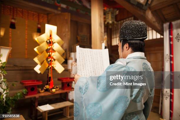 rear view of priest holding scroll at shinto sakurai shrine, fukuoka, japan. - shrine stock pictures, royalty-free photos & images