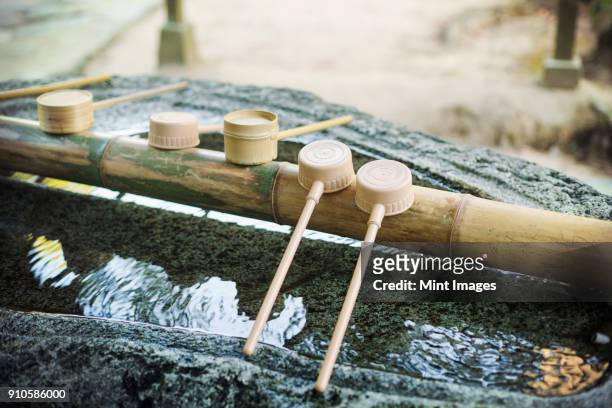 close up of bamboo water hand washing basins at shinto sakurai shrine, fukuoka, japan. - shrine fotografías e imágenes de stock