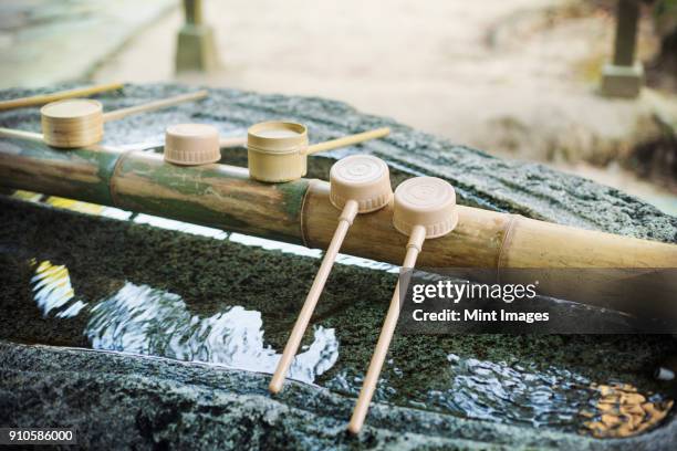 close up of bamboo water hand washing basins at shinto sakurai shrine, fukuoka, japan. - shrine stock pictures, royalty-free photos & images