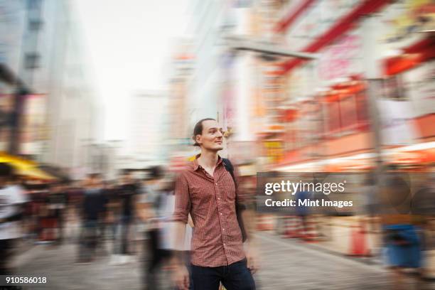 a western man in tokyo on the street, looking around him. long exposure, blurred background effect. - esposizione lunga foto e immagini stock