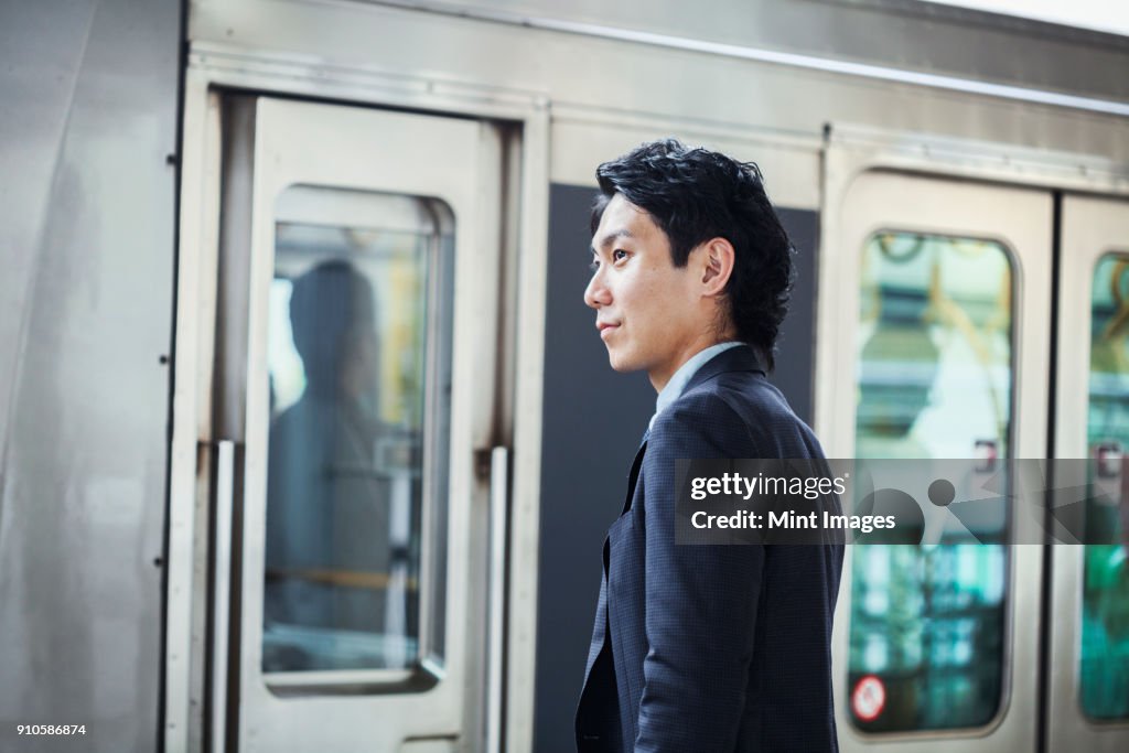 Businessman wearing suit standing at train station platform.