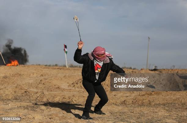 Palestinian protester throws a rock in response to Israeli security forces' intervention during a protest against U.S. President Donald Trumps...