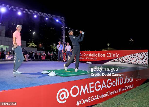 Rory McIlroy of Northern Ireland givews a lesson to Arjun Gupta the winner of the competition to win a lesson with Rory hits a shot watched by Niall...