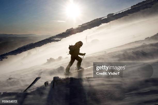 esquiador parte país escalar una montaña en una tormenta severa. - manage fotografías e imágenes de stock