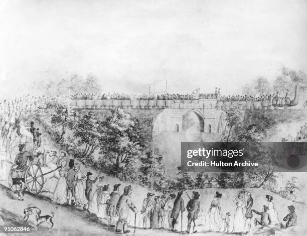 Crowds gather to watch the opening of the Stockton and Darlington Railway in north-east England, 1825. The railway is passing over the River Skerne...