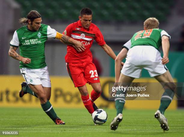 Per Mertesacker and Torsten Frings of Bremen as well as Deniz Naki of St. Pauli battle for the ball during the DFB Cup second round match between SV...