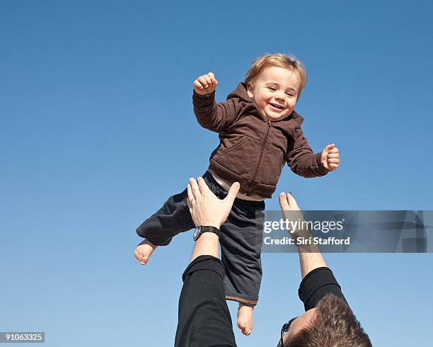 father tossing young boy up in air - siri stafford stock pictures, royalty-free photos & images