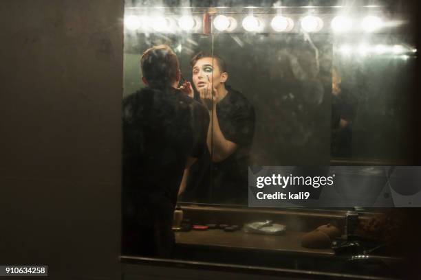 young man in dressing room applying make-up - backstage mirror stock pictures, royalty-free photos & images