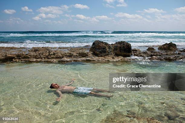 man floats on back in tropical tide pool - arm floats stock-fotos und bilder