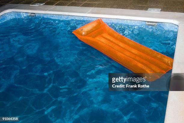 orange air mattress on top of blue water in pool - pool raft stock pictures, royalty-free photos & images