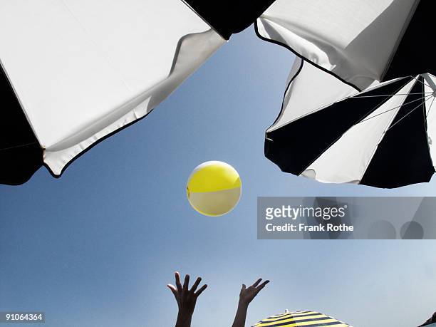 water ball up in the air on beach with umbrellas - ball and hand in the air stockfoto's en -beelden