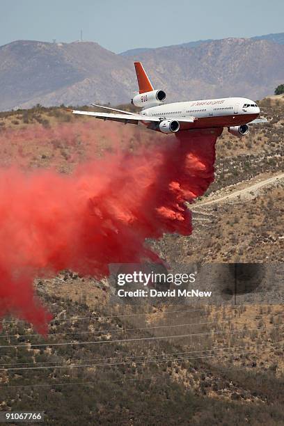 Firefighting DC-10 jumbo jet drops thousands of gallons of fire retardant to create a fireline on the southeastern flank of the nearly 10,000-acre...