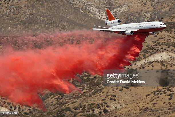 Firefighting DC-10 jumbo jet drops thousands of gallons of fire retardant to create a fireline on the southeastern flank of the nearly 10,000-acre...