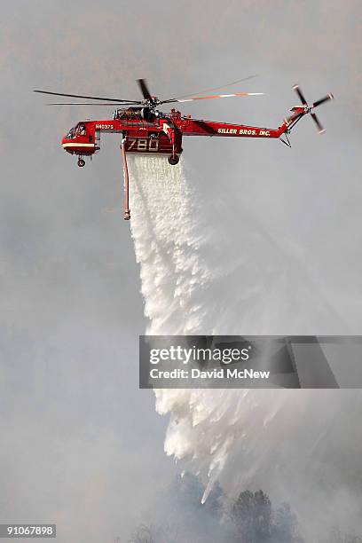 Firefighting helicopter drops water along the southeastern flank of the nearly 10,000-acre Guiberson fire, burning out of control for a second day as...