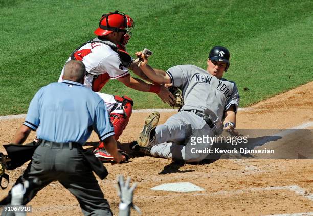 Mark Teixeira of the New York Yankees is tagged out at home plate by catcher Mike Napoli of the Los Angeles Angels of Anaheim on a throw from left...