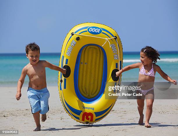 kids running with inflatable boat on beach - inflatable stock pictures, royalty-free photos & images