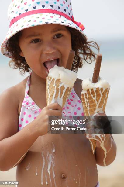 girl eating two melting ice creams - girl eating messy ice cream cone stock pictures, royalty-free photos & images