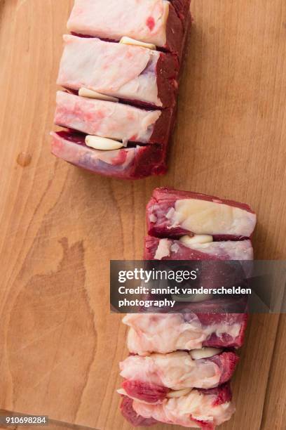 slivers of garlic in incision spots chuck meat. - incision stock pictures, royalty-free photos & images