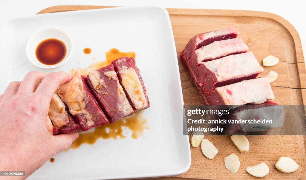 Chuck beef with slivers of garlic having been rolled in soy sauce.