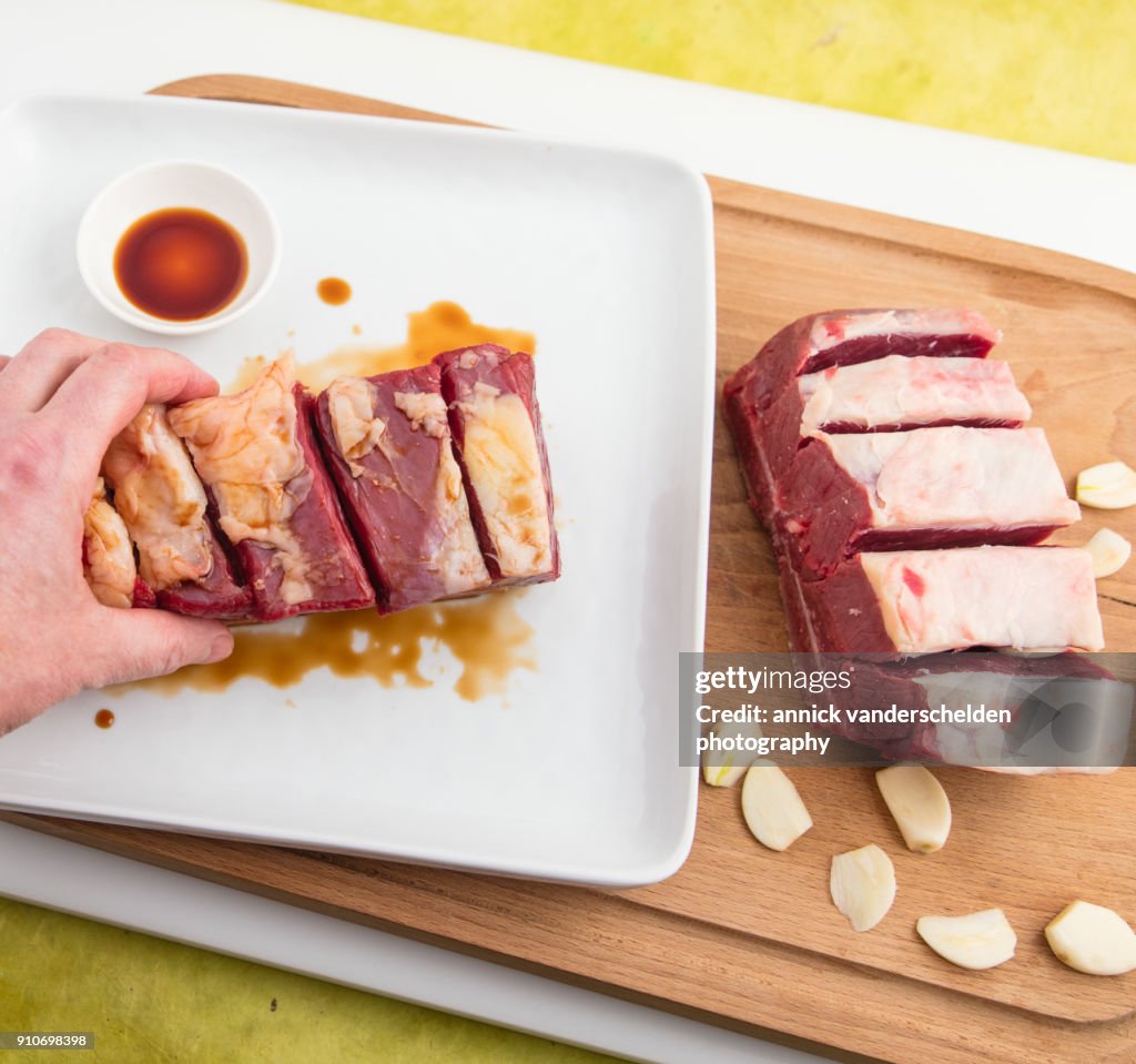 Chuck beef with slivers of garlic having been rolled in soy sauce.