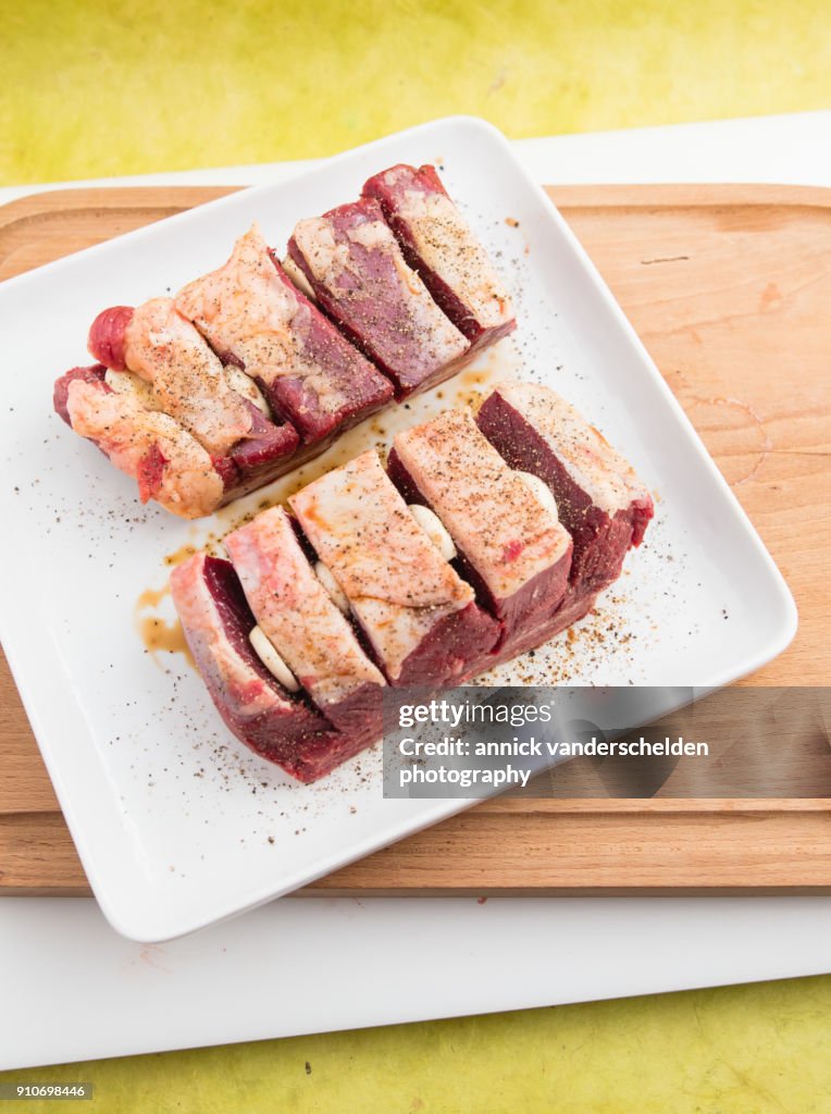 Chuck beef with slivers of garlic having been rolled in soy sauce.