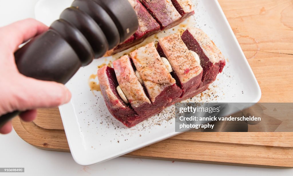 Chuck beef with slivers of garlic having been rolled in soy sauce.