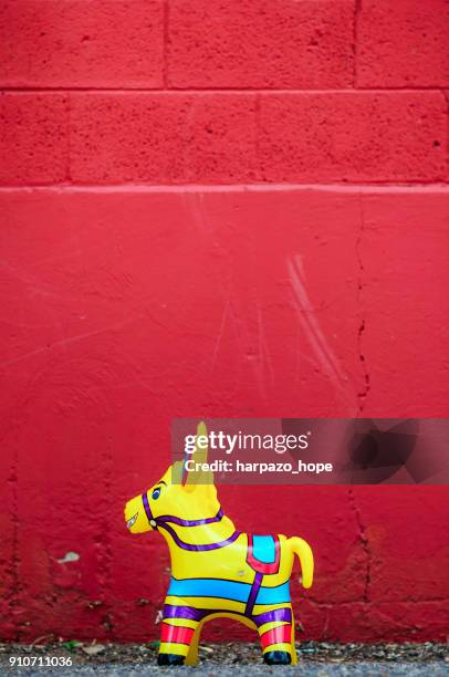 yellow donkey toy and a red wall. - harpazo hope stock pictures, royalty-free photos & images