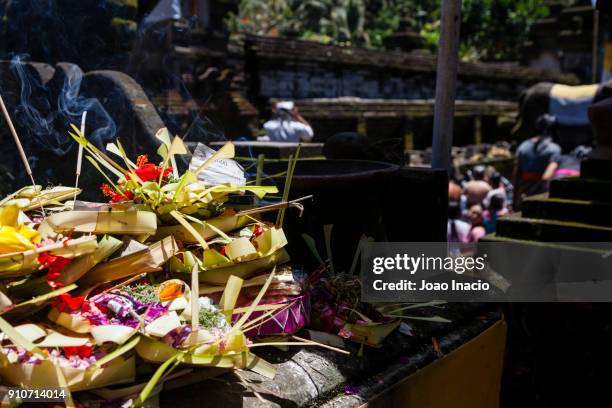 pallets of offerings (canang sari) at tirta empul temple (hindu balinese water temple), bali, indonesia - tirta empul temple stock pictures, royalty-free photos & images