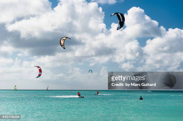 kite surfers skimming across turquoise blue waters on a beautiful day at hadicuri beach, noord, aruba - noord amerika stock-fotos und bilder